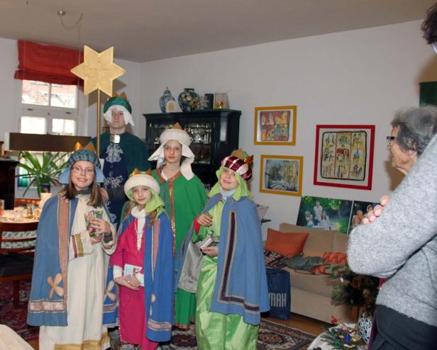 Eine Gruppe Kinder, verkleidet als die Heiligen Drei Könige, steht in einem Wohnzimmer.