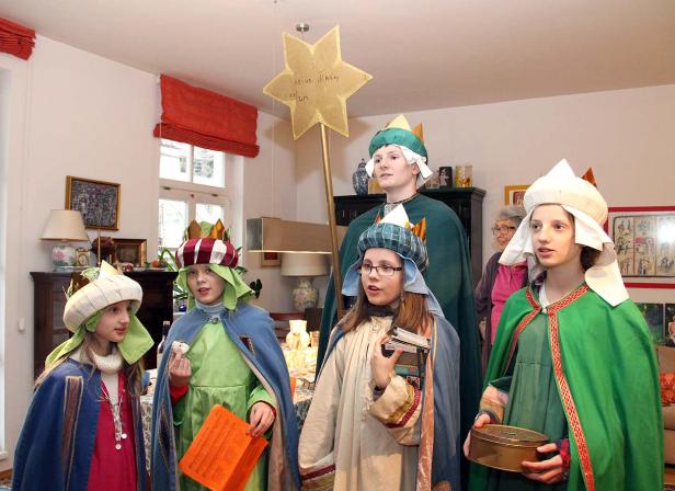 Eine Gruppe Kinder, verkleidet als Sternsinger, steht in einem Raum.