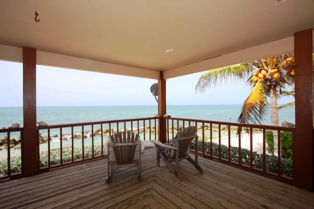 Zwei Holzstühle stehen auf einer Veranda mit Blick auf das Meer.