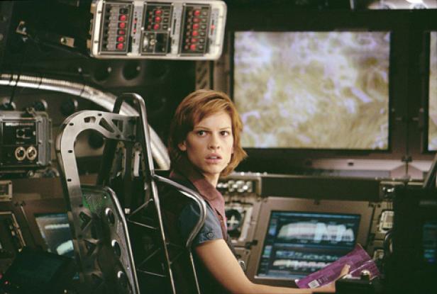 Hilary Swank sitzt in einem Raumschiff-Cockpit und blickt besorgt zur Seite.