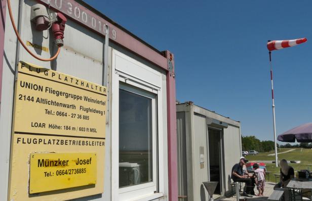 Ein Flugplatz mit Containern, einer Windhose und einer Gruppe von Menschen an einem Tisch.