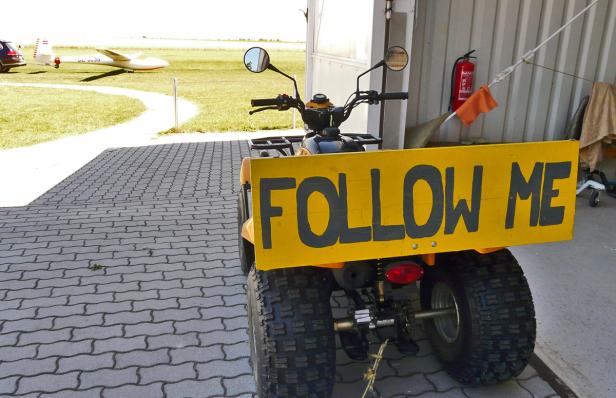 Ein gelbes Quad mit einem Schild „Follow Me“ auf einem Flugplatz.