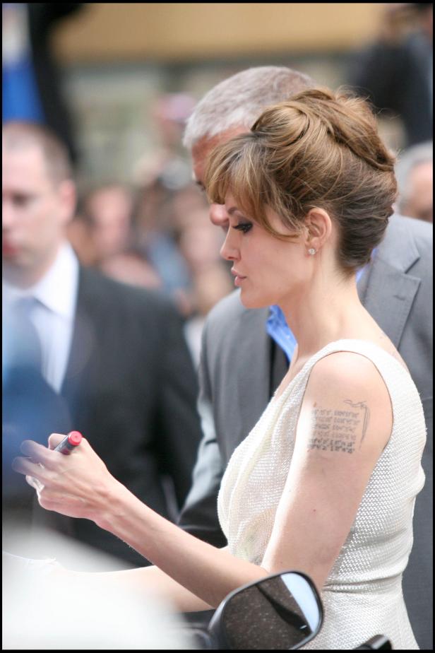 Angelina Jolie signiert Autogramme in einem hellen Kleid.
