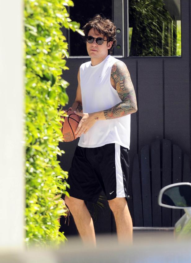 John Mayer mit Tätowierungen hält einen Basketball in der Hand.