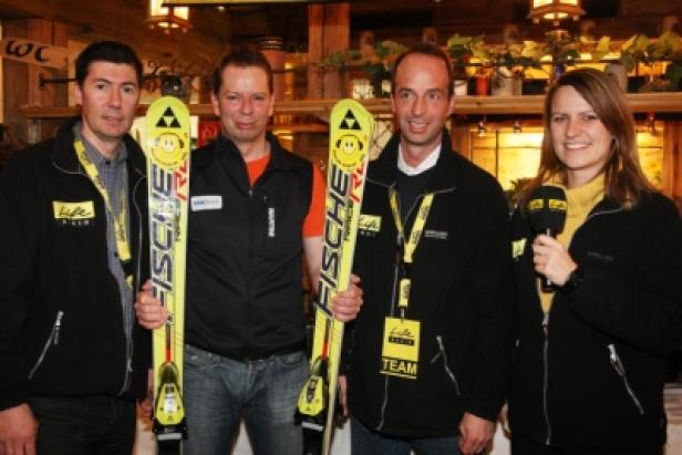 Vier Personen posieren mit gelben Fischer-Ski für ein Foto.