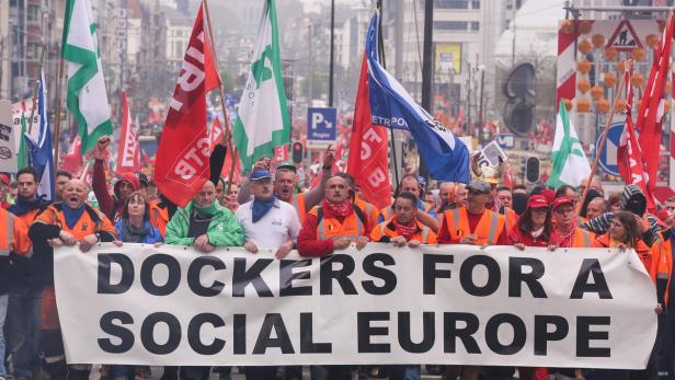Eine Demonstration von Hafenarbeitern für ein soziales Europa mit vielen Flaggen.
