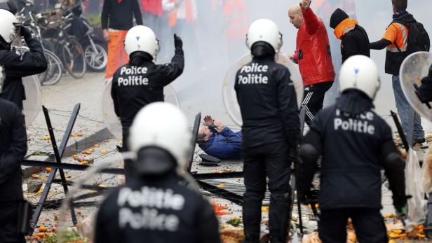 Ein Mann liegt am Boden, umringt von Polizisten mit Schilden.