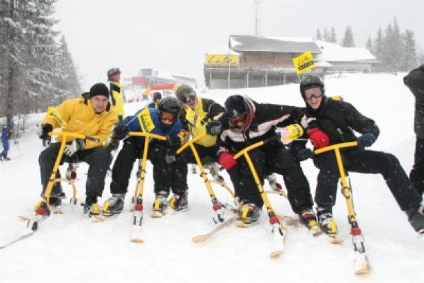 Eine Gruppe von Menschen fährt mit Skibikes auf einer schneebedeckten Piste.
