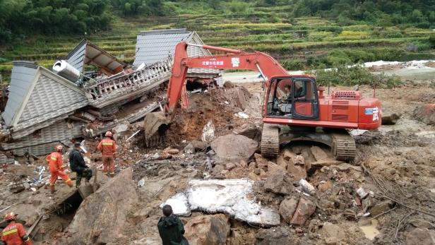 Ein Bagger steht vor den Trümmern eines durch ein Unglück zerstörten Hauses.