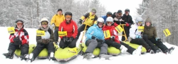 Eine Gruppe von Menschen sitzt auf Schnee und hält gelbe Fahnen.