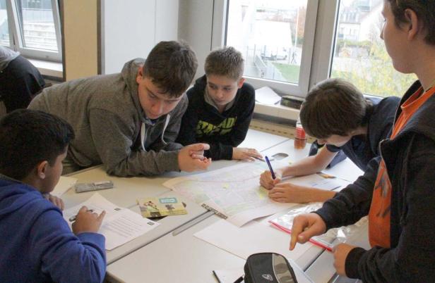 Eine Gruppe von Schülern arbeitet gemeinsam an einem Tisch an einer Karte.