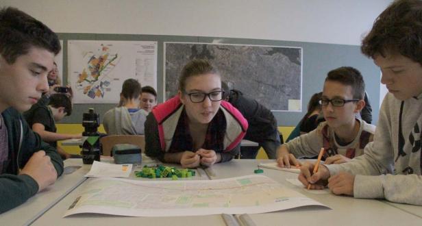 Schüler arbeiten gemeinsam an einem Projekt mit Karten und Legosteinen.