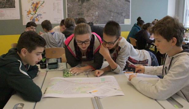 Schüler arbeiten gemeinsam an einem Tisch an einer Karte.