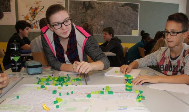 Schüler planen mit Legosteinen auf einem Stadtplan im Klassenzimmer.