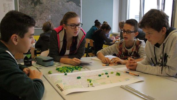 Eine Gruppe von Schülern arbeitet an einem Plan mit grünen Blöcken.