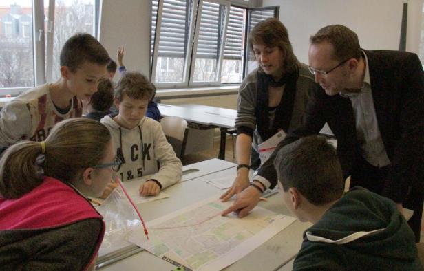 Eine Gruppe von Schülern und Lehrern betrachtet eine Karte auf einem Tisch.