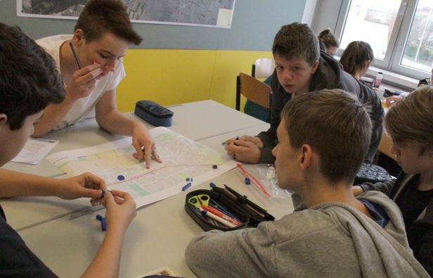 Eine Gruppe von Schülern plant eine Route auf einer Stadtkarte mit blauen Markierungen.