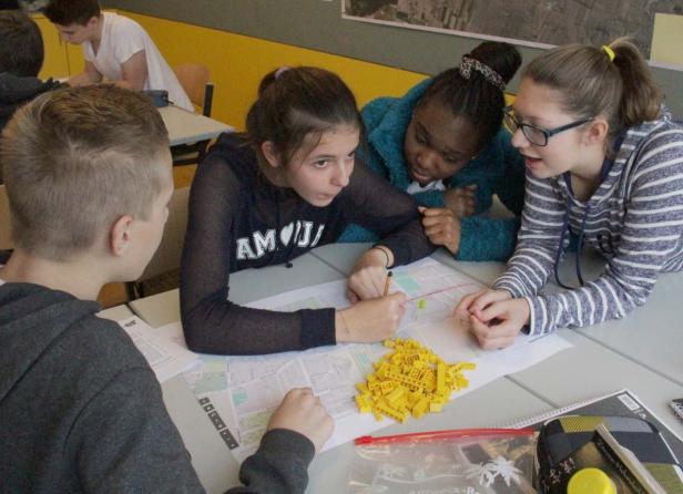 Eine Gruppe von Schülern arbeitet gemeinsam an einem Projekt mit einer Karte und Legosteinen.