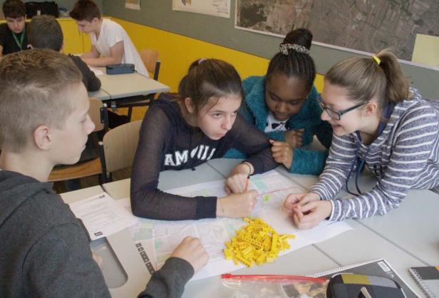 Eine Gruppe von Schülern arbeitet an einem Projekt mit einer Karte und Legosteinen.
