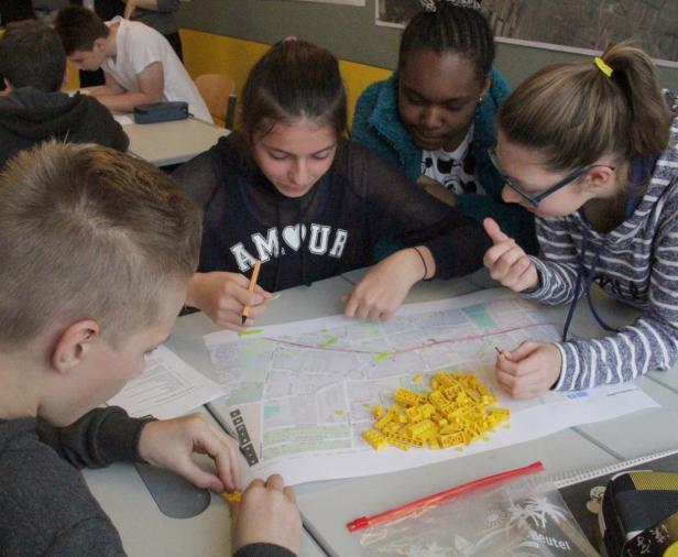 Eine Gruppe von Schülern arbeitet gemeinsam an einer Karte mit Legosteinen.