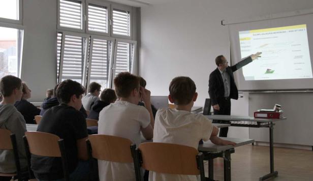 Ein Lehrer präsentiert Raumplanung vor einer Klasse Schülern.