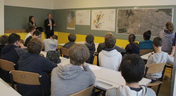 Ein Lehrer hält vor einer Klasse einen Vortrag über Stadtpläne.