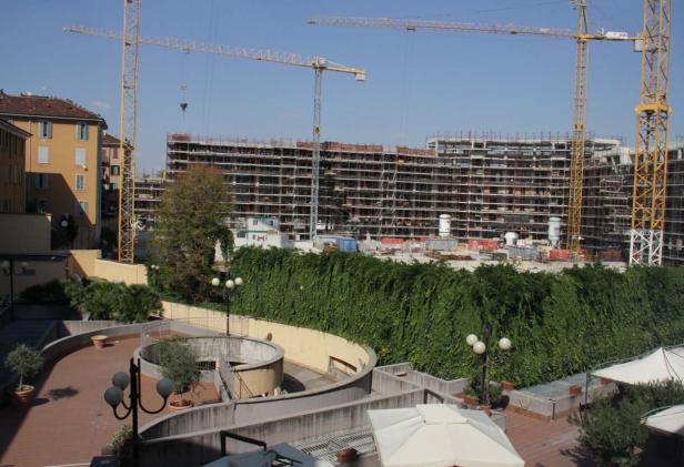Blick auf eine Baustelle mit mehreren Kränen und einem im Bau befindlichen Gebäude.