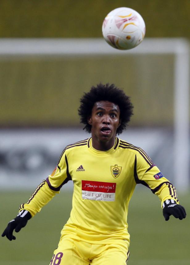 Ein Fußballspieler in gelbem Trikot blickt zu einem fallenden Ball.