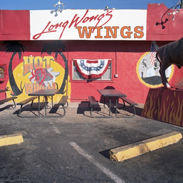 Das Restaurant Long Wong's Wings mit Tischen im Freien und einem Stier als Dekoration.