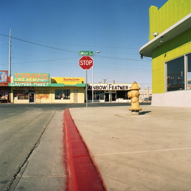 Eine Straßenszene mit einem Hydranten und Geschäften wie „Rainbow Feather“ und „Llantera Tires“.