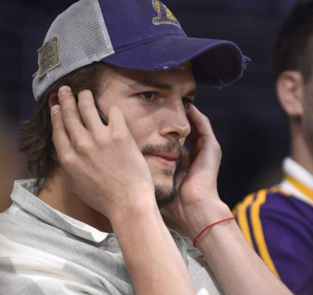 Ashton Kutcher mit einer Baseballkappe telefoniert.