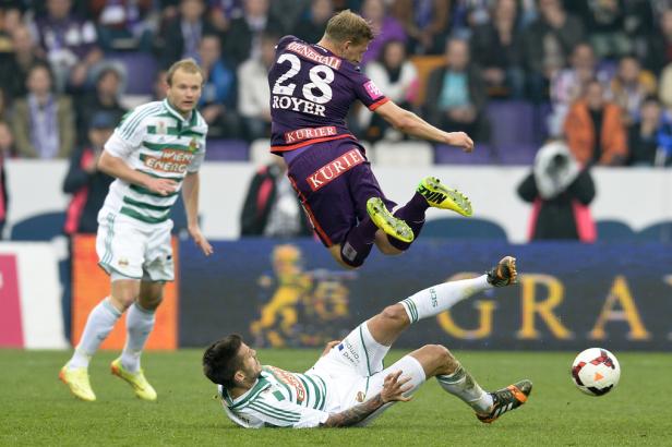 Ein Fußballspieler springt über einen am Boden liegenden Spieler, um den Ball zu erreichen.