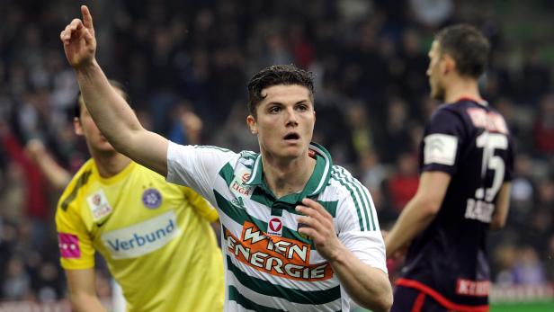 Ein Fußballspieler im grün-weißen Trikot von Rapid Wien zeigt mit dem Finger nach oben.