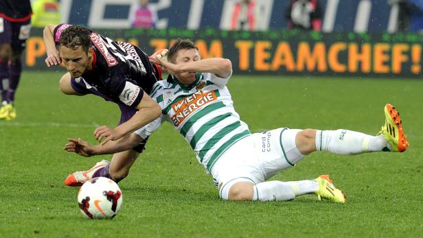 Zwei Fußballspieler kämpfen um den Ball auf dem Rasen.