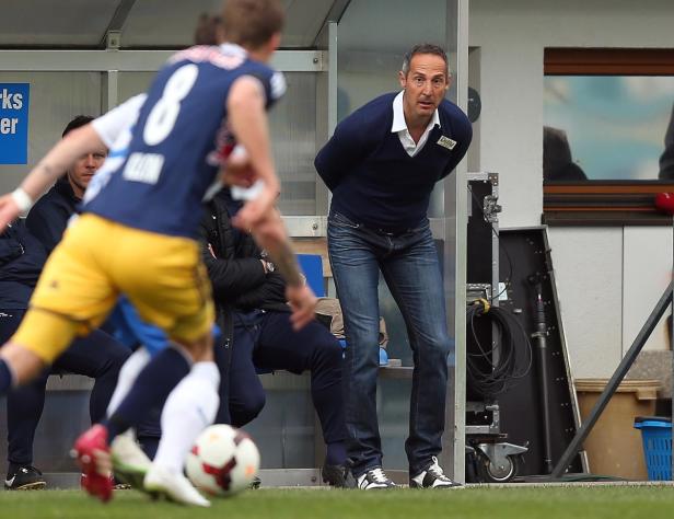 Ein Fußballtrainer beobachtet ein Fußballspiel vom Spielfeldrand aus.