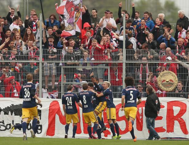 Fußballspieler von Red Bull feiern vor jubelnden Fans ein Tor.