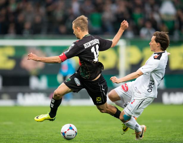 Zwei Fußballspieler kämpfen um den Ball auf dem Spielfeld.
