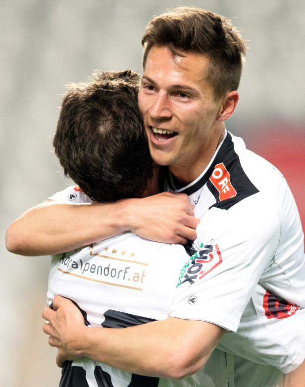 Zwei Fußballspieler umarmen sich freudig.