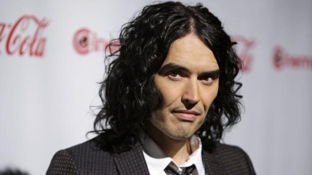 Porträt von Russell Brand mit dunklen, lockigen Haaren und einem Anzug.