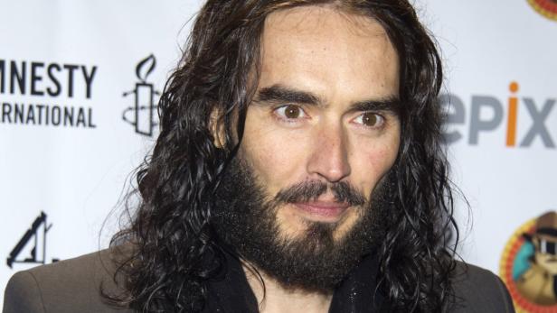 Porträt von Russell Brand mit Bart und langen, dunklen Haaren.