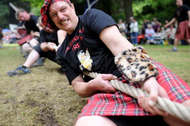 Männer im Kilt ziehen an einem Seil beim Tauziehen.