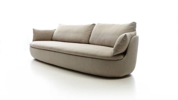 Ein beiges Sofa mit Kissen steht auf einem weißen Hintergrund.