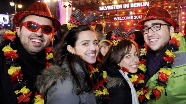 Eine Gruppe von Menschen feiert Silvester in Berlin mit Deutschland-Dekorationen.