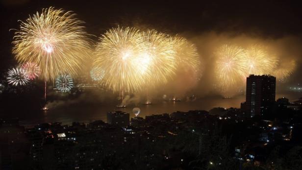Goldene Feuerwerke erhellen den Nachthimmel über einer Stadt.