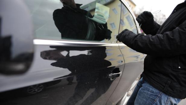 Eine Person versucht, ein Auto mit einem Draht aufzubrechen.