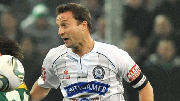 Ein Fußballspieler im weißen Trikot mit dem Ball am Fuß.