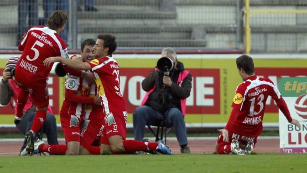 Fußballspieler in roten Trikots feiern ein Tor auf dem Spielfeld.