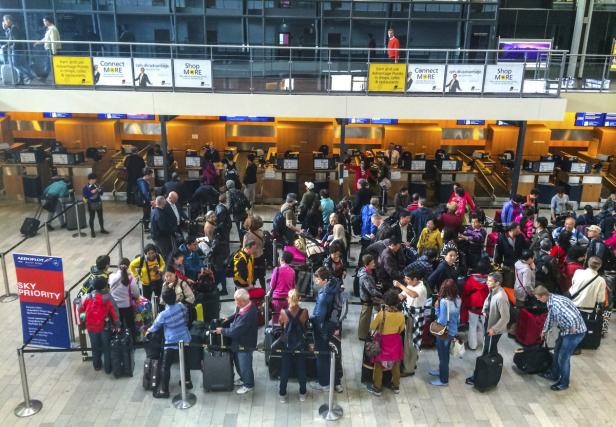 Viele Reisende stehen an den Check-in-Schaltern eines Flughafens an.