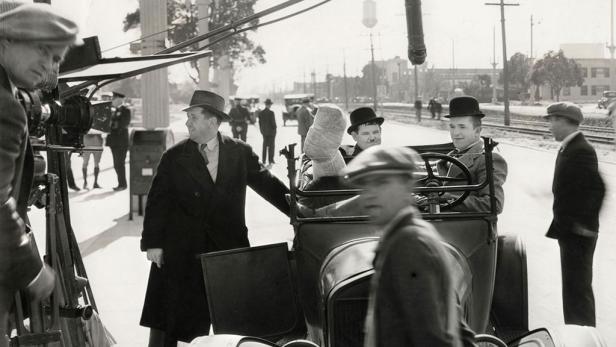 Dreharbeiten mit Stan Laurel und Oliver Hardy in einem Auto.
