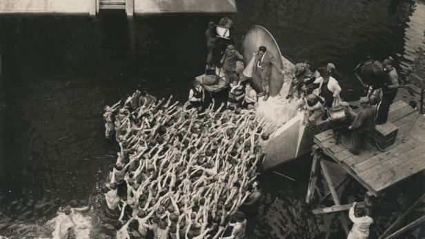 Eine Filmszene mit vielen Menschen im Wasser, die ihre Arme ausstrecken.